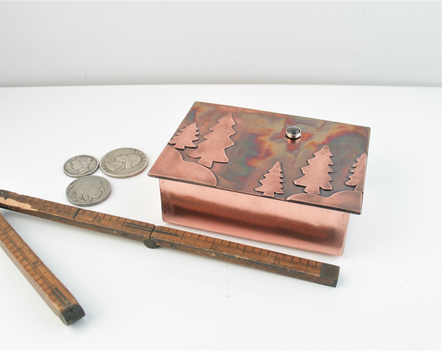 Hinge lid copper box with trees and hills on lid showing size related to common objects
