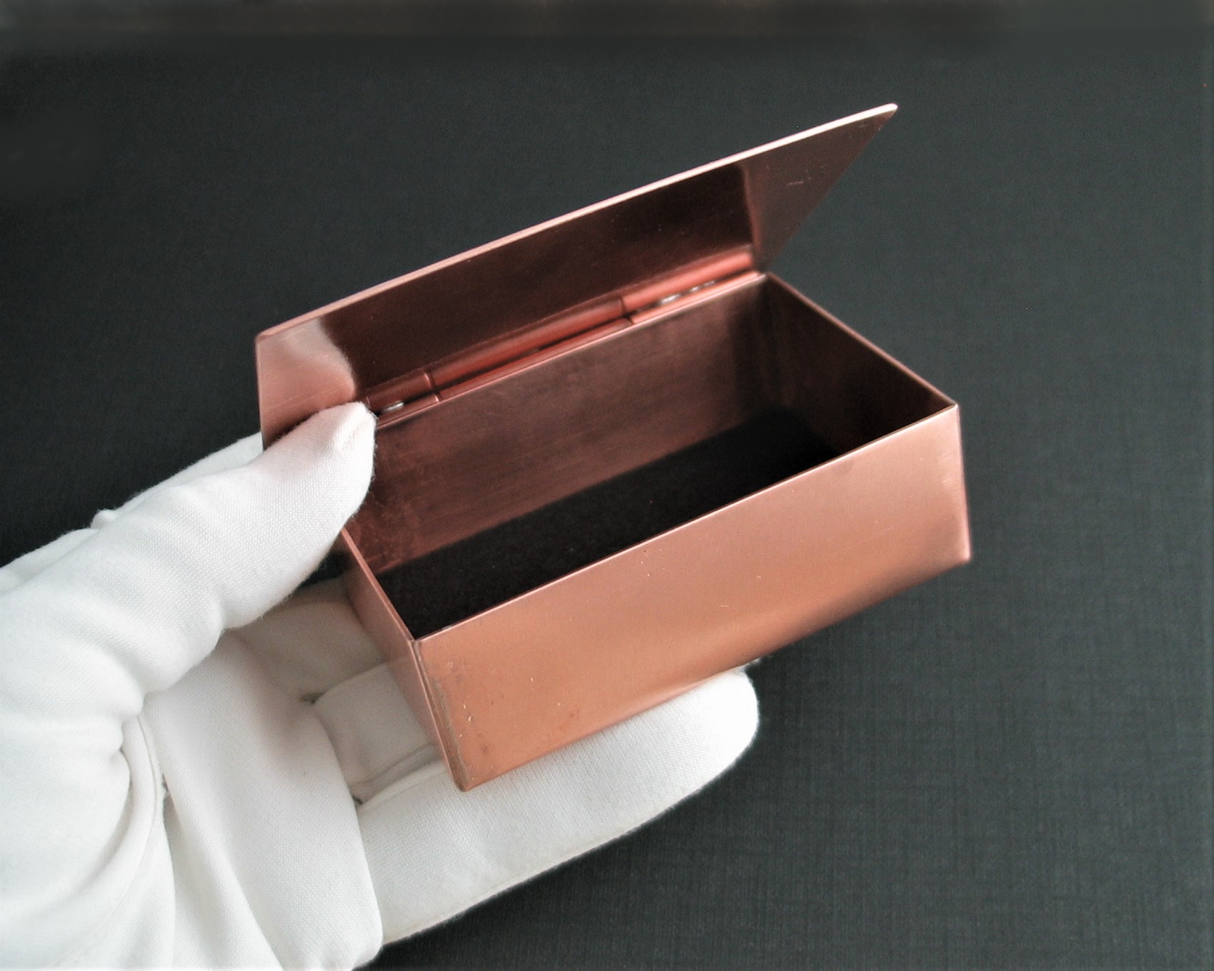 Inside of solid copper trinket box 3" x 2" with enameled lid with silhouettes of trees and running wolves