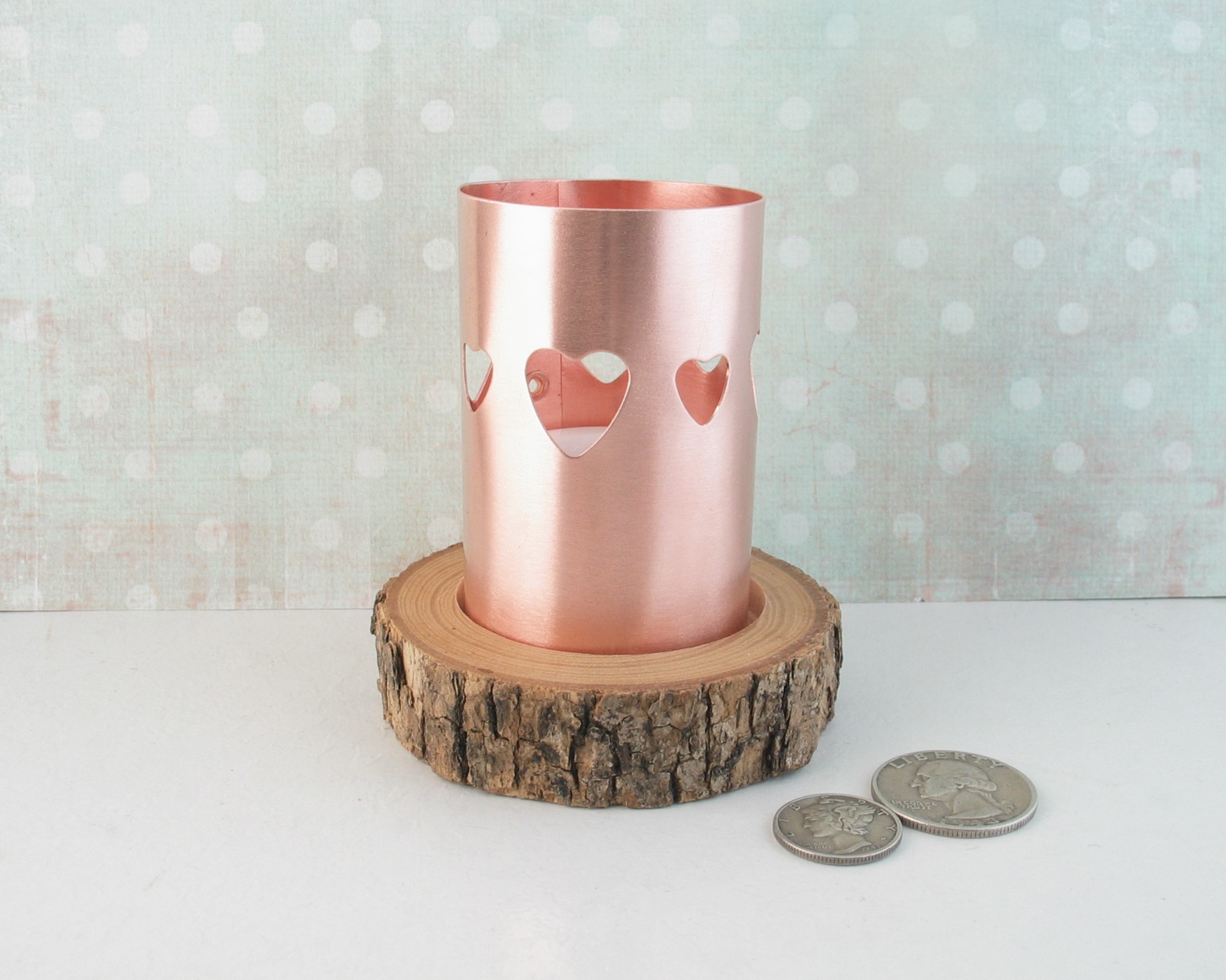 Scandanavian style heart-pierced copper chimney tea light candle holder on live-edge wooden base cut from tree limb. comes with flameless tealight candle. shown with dime and quarter for size comparison