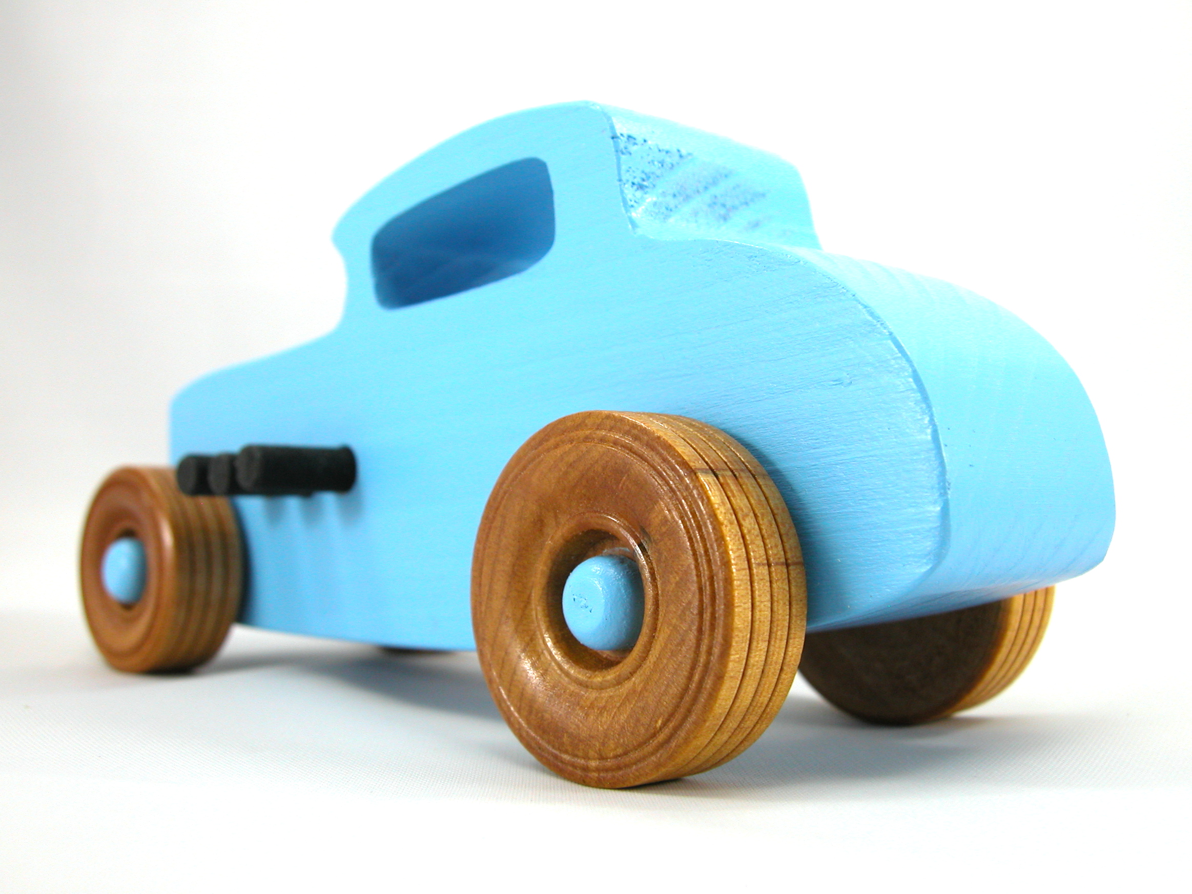 A wooden handmade hot rod toy car modeled after a 32 Deuce Coupe, painted in baby blue and black acrylic paint, with non-marring Amber Shellac wheels.