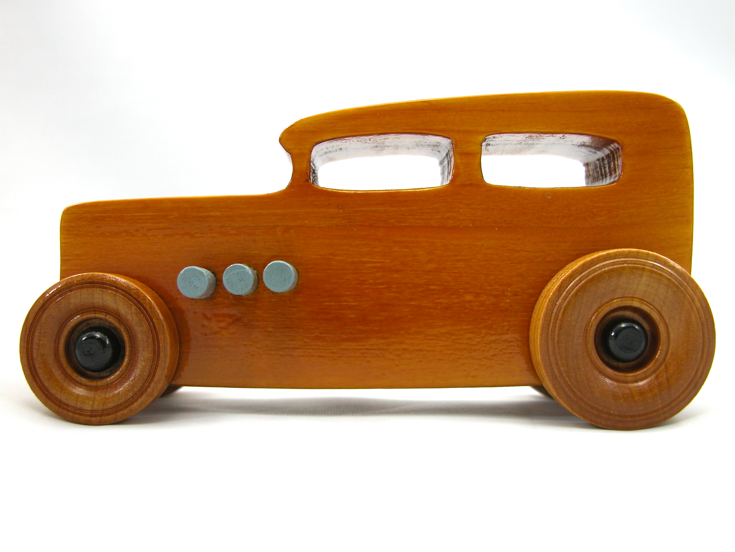 This handmade wooden toy car is based on a 1932 Ford Sedan Hot Rod. It is hand-finished with multiple coats of amber shellac and trimmed with black and grey acrylic paint.