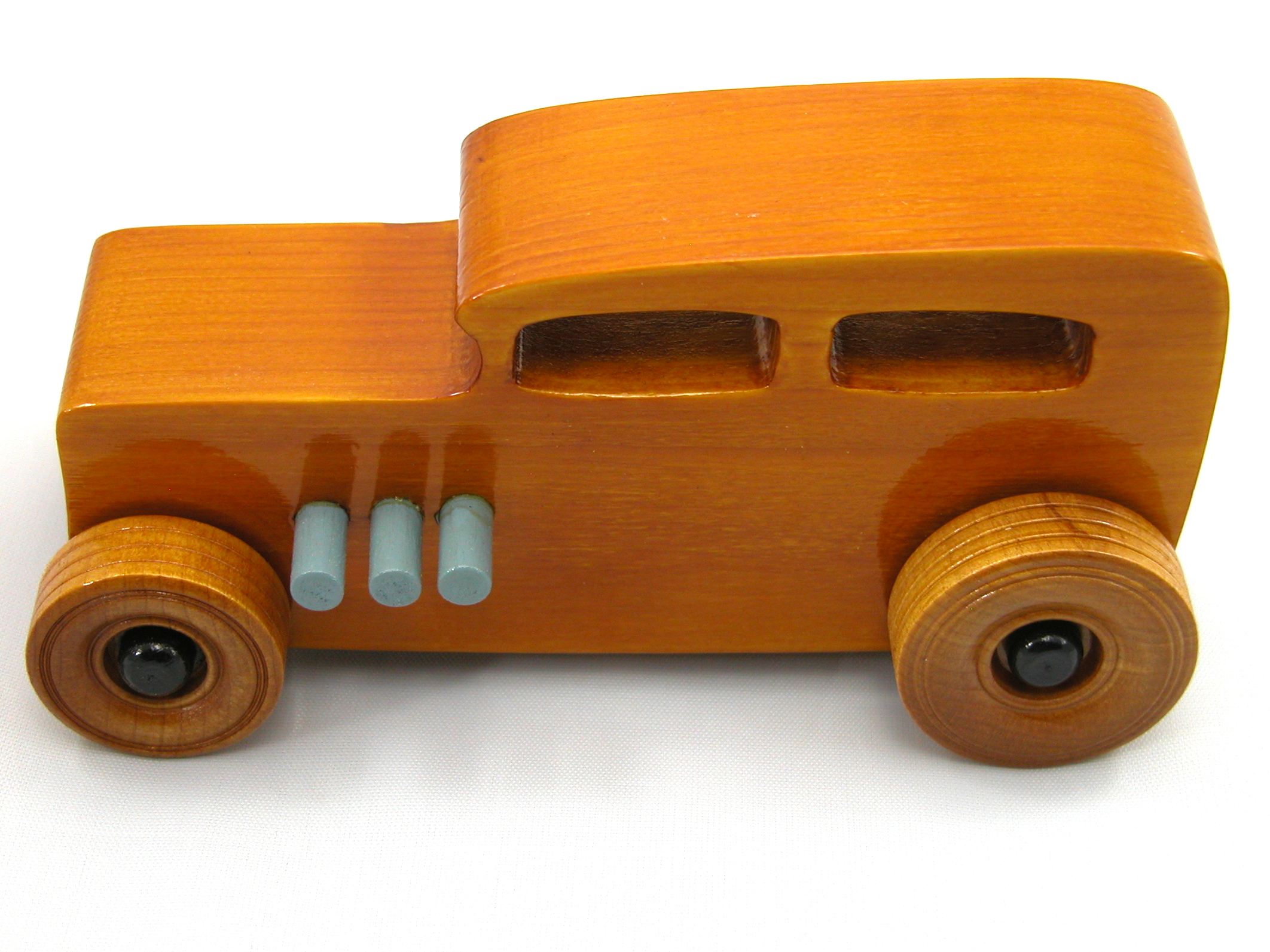 This handmade wooden toy car is based on a 1932 Ford Sedan Hot Rod. It is hand-finished with multiple coats of amber shellac and trimmed with black and grey acrylic paint.