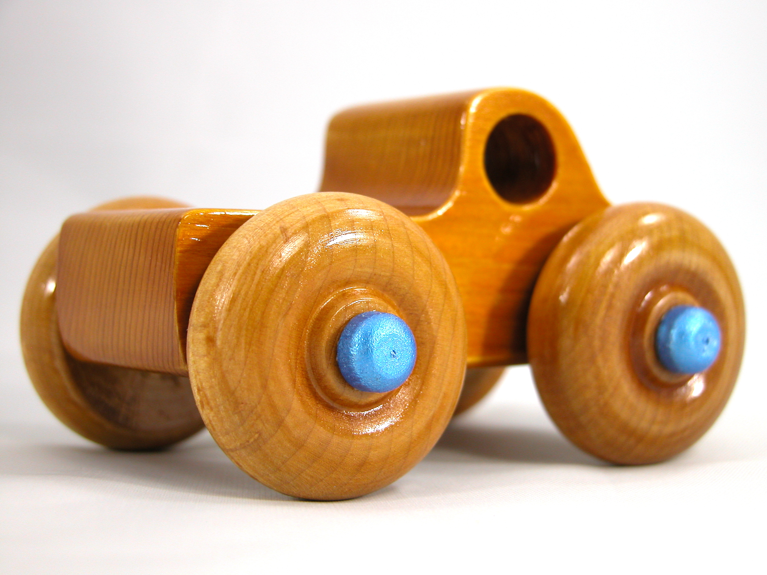 Handmade Wooden Toy Truck With Round Windows Finished with Glossy Amber Shellac and Metallic Sapphire Blue Acrylic Paint trim. Excellent, durable push toy for toddlers with chunky wheels that roll well on any surface.