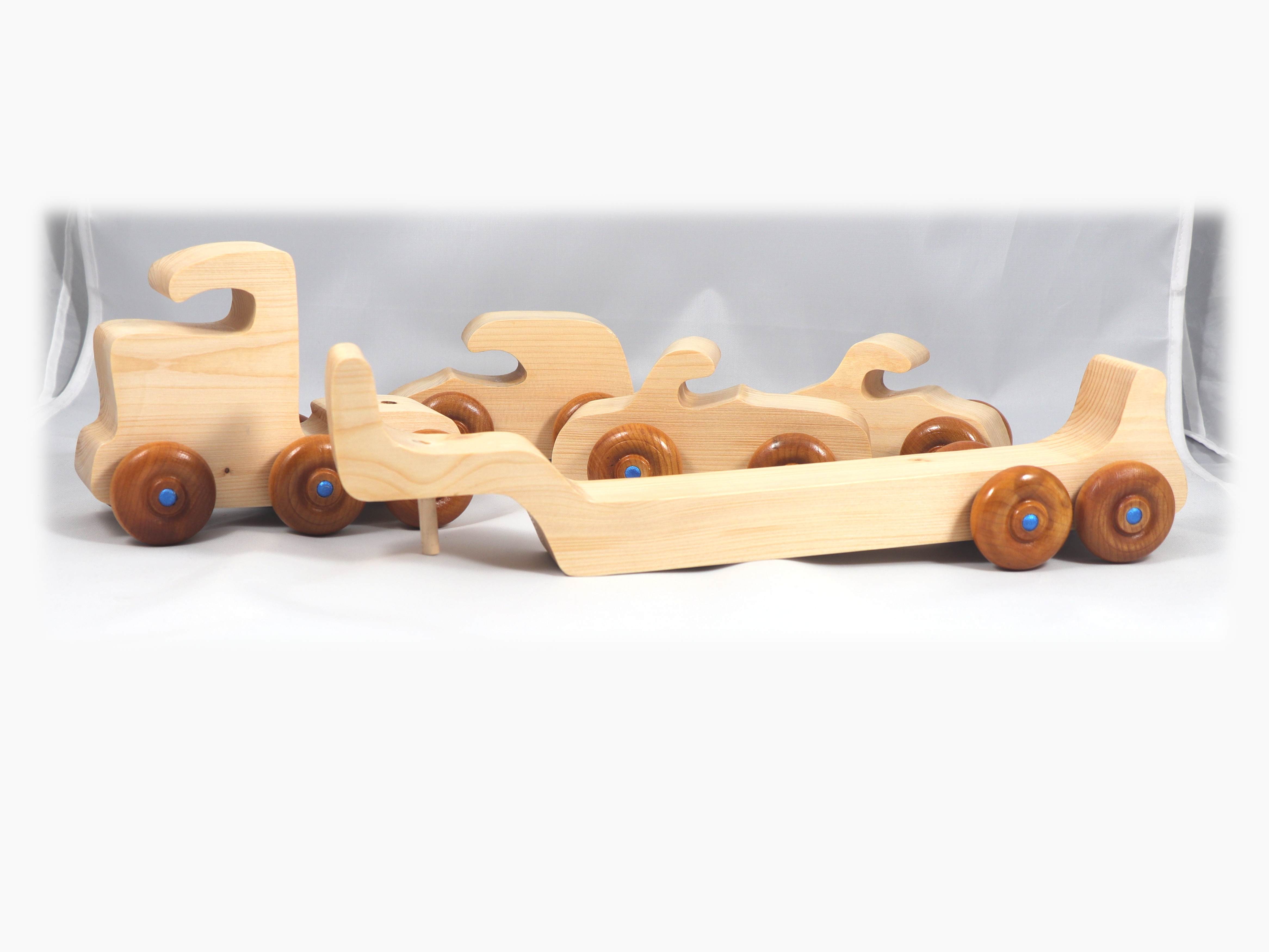 Handmade wooden toy truck play set includes three cars and a tractor-trailer finished with clear and amber shellac with metallic sapphire blue trim.