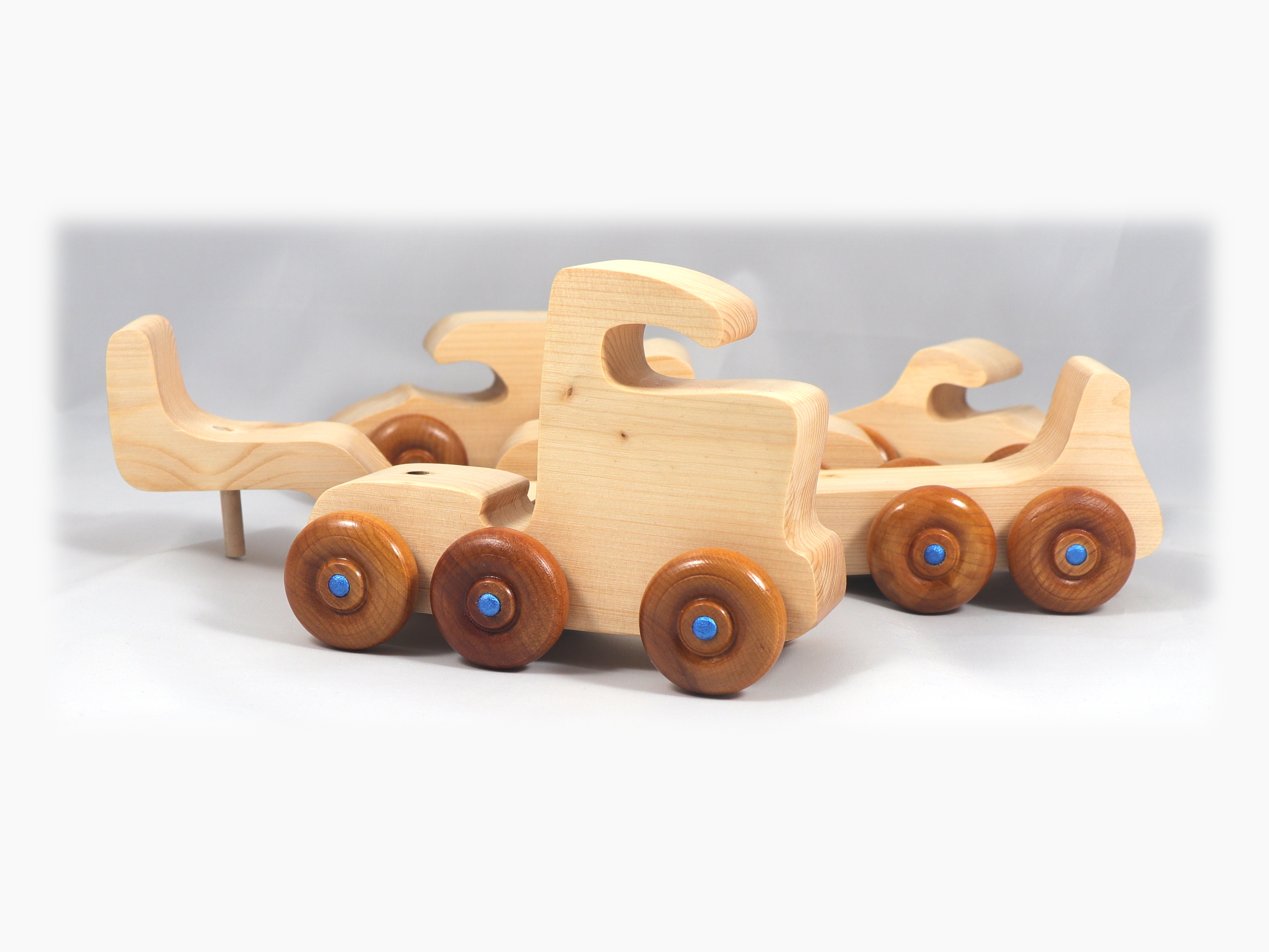 Handmade wooden toy truck play set includes three cars and a tractor-trailer finished with clear and amber shellac with metallic sapphire blue trim.