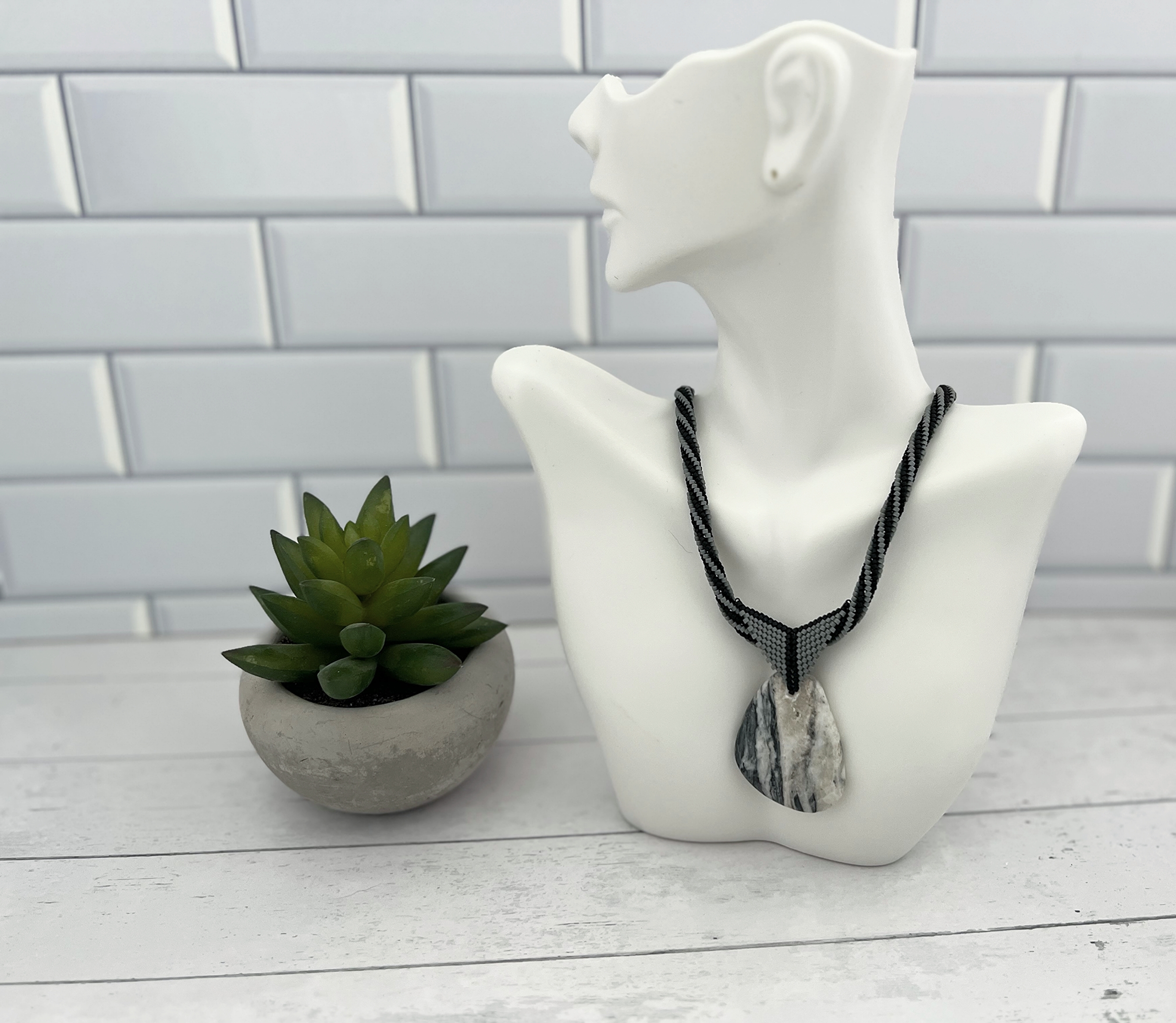 Black and grey beaded necklace shown on bust display.