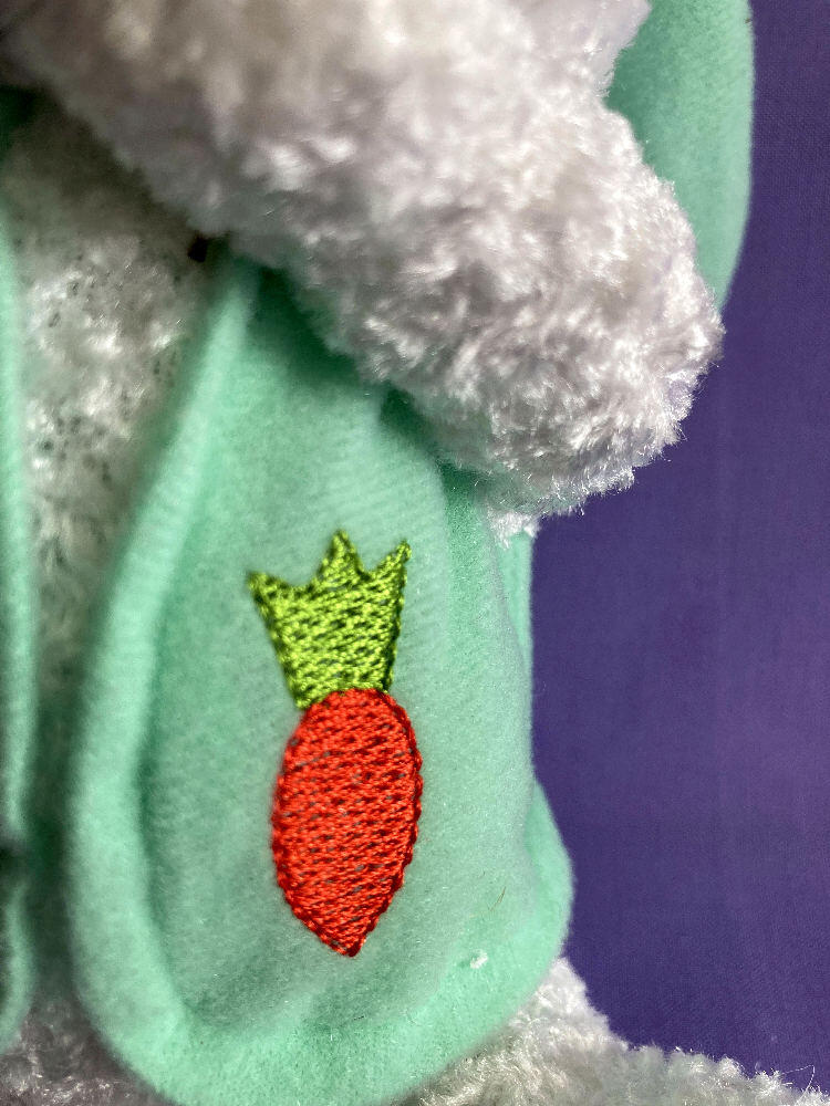 Close up of green vest with carrot embroidered on front.