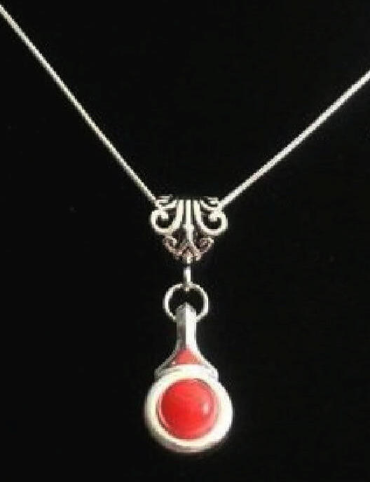Beautiful Coral stone is viewed on a flute trill key.  A fleur de lis bail on a  16" silver plated snake chain.