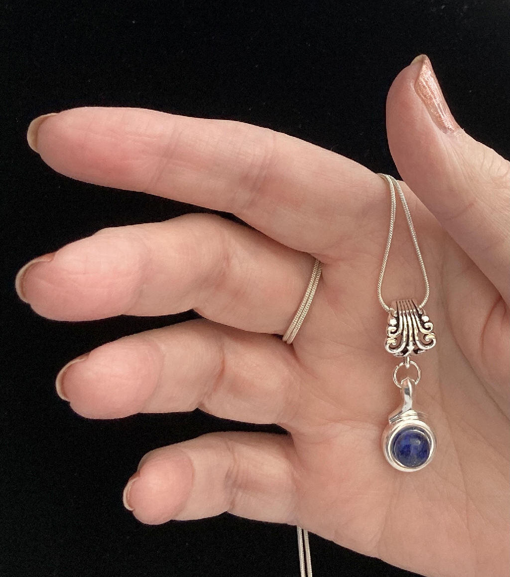 Beautiful Lapis stone is viewed on a flute trill key.  A fleur de lis bail on a  16" silver plated snake chain.