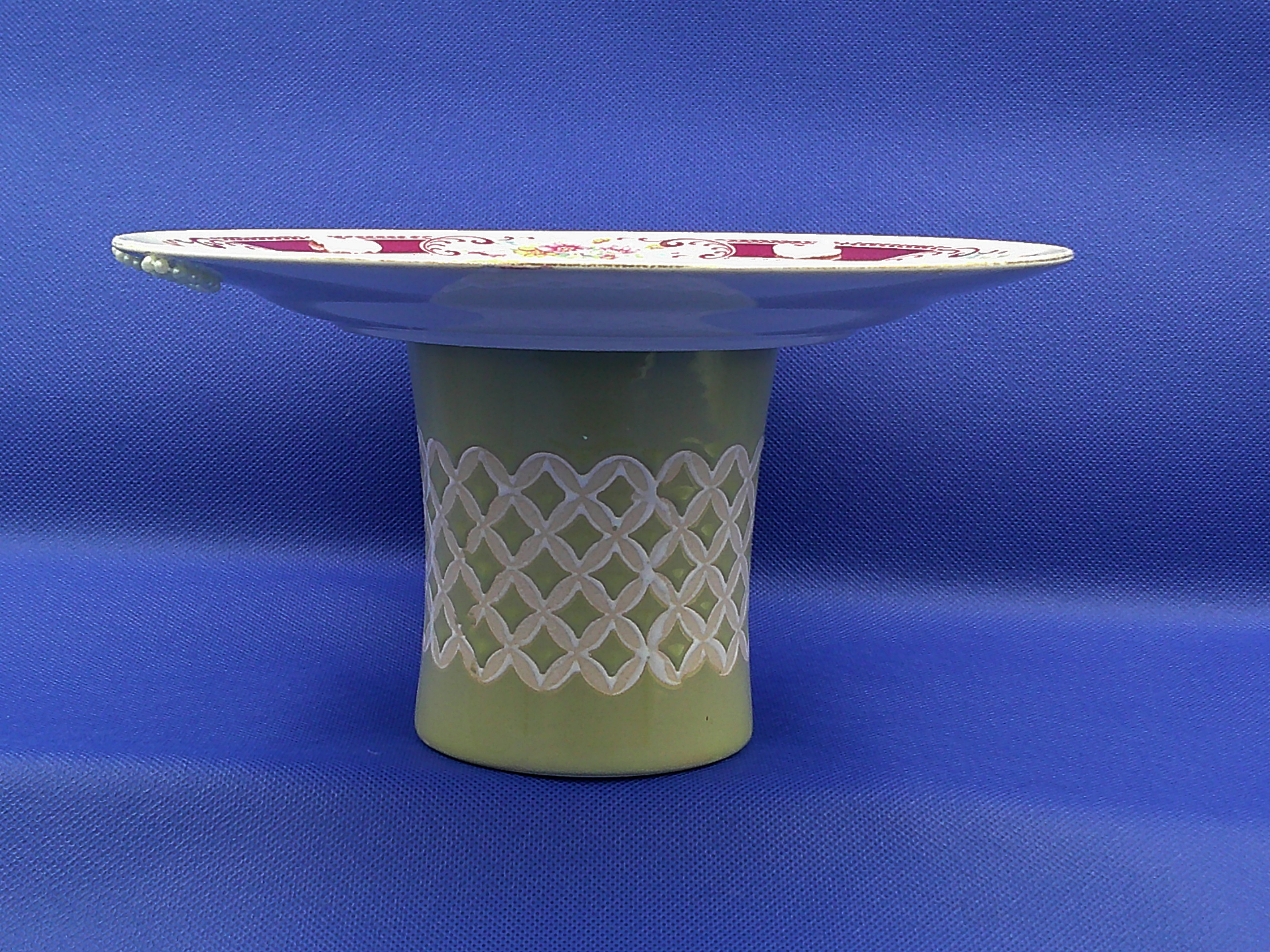 This shows the lattice work on the "stand". The faint white trim in the lattice matches the lace on the plate. This shows the lattice work on the "stand". The faint white trim in the lattice matches the lace on the plate.