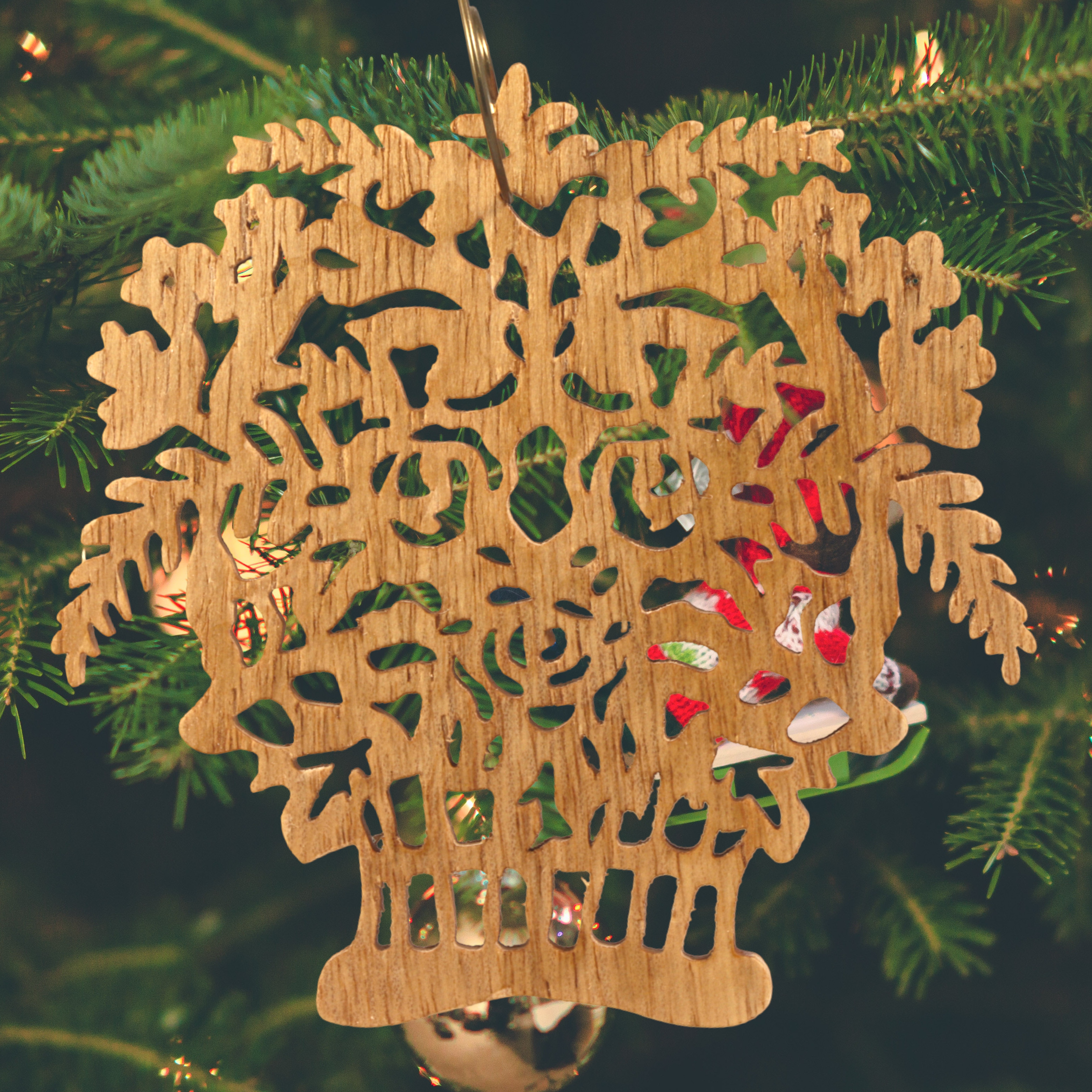 A handcrafted Victorian-style wooden Christmas tree ornament shaped like a basket filled with intricate floral designs, featuring detailed leaves and blossoms, with a small hook at the top for hanging.