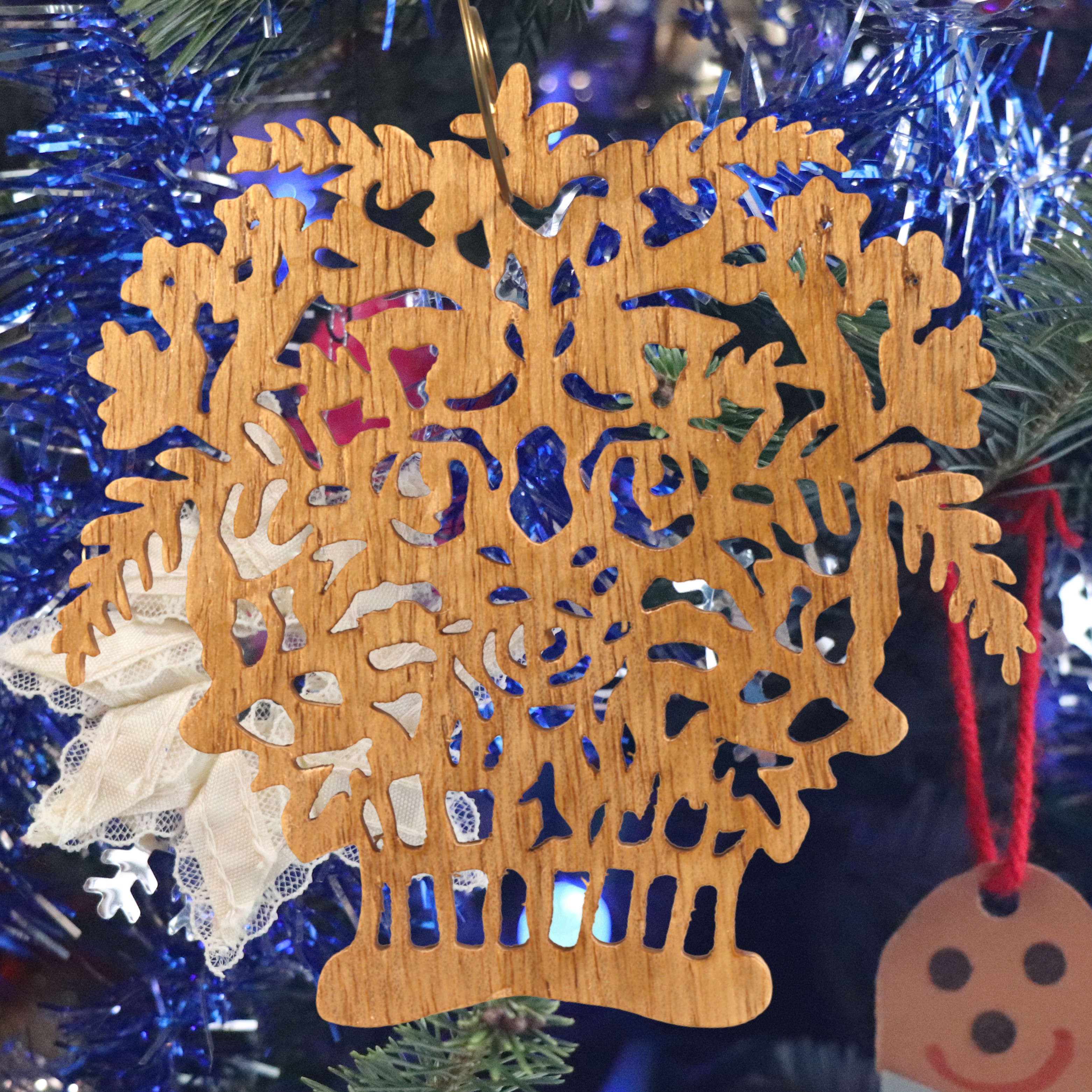 A handcrafted Victorian-style wooden Christmas tree ornament shaped like a basket filled with intricate floral designs, featuring detailed leaves and blossoms, with a small hook at the top for hanging.