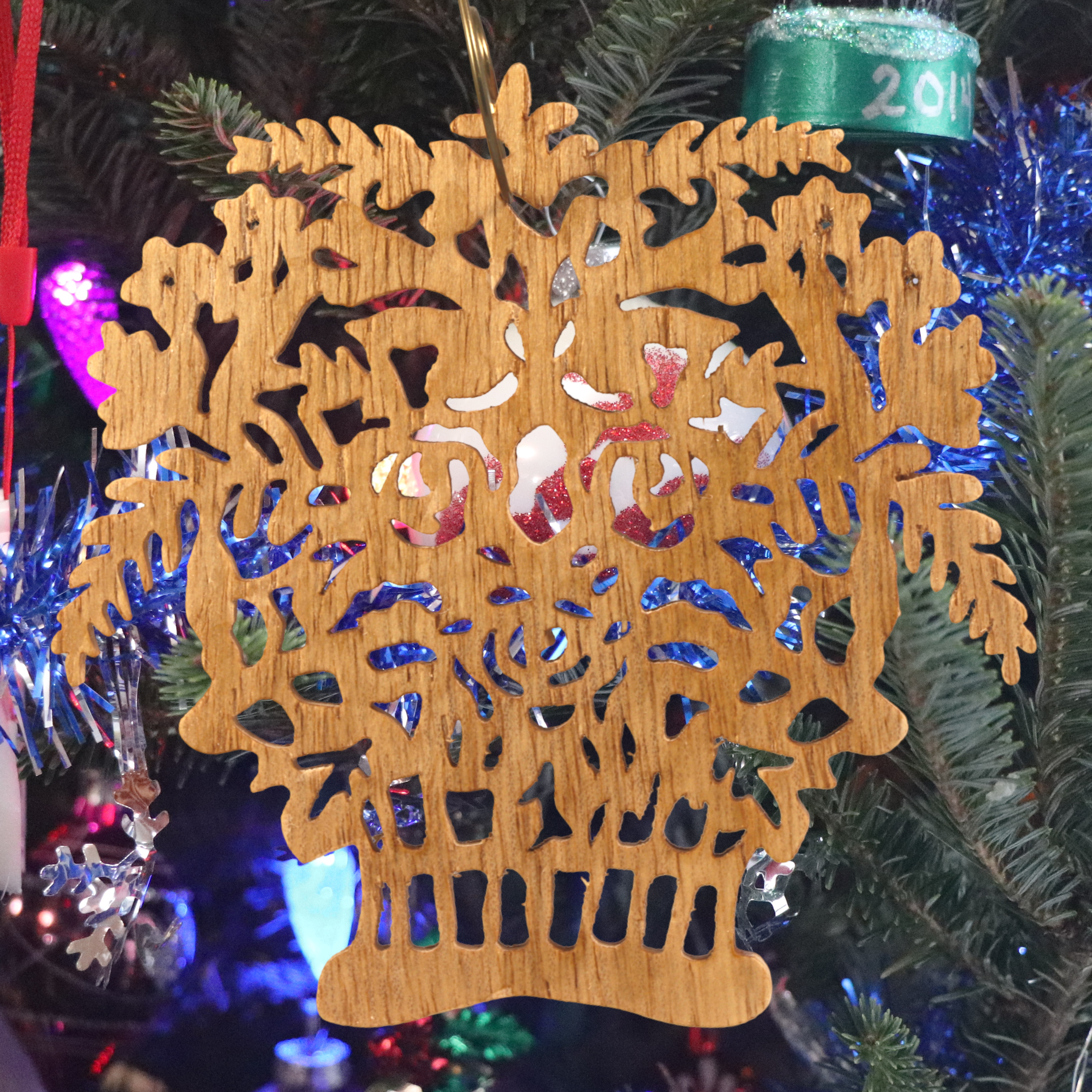 A handcrafted Victorian-style wooden Christmas tree ornament shaped like a basket filled with intricate floral designs, featuring detailed leaves and blossoms, with a small hook at the top for hanging.