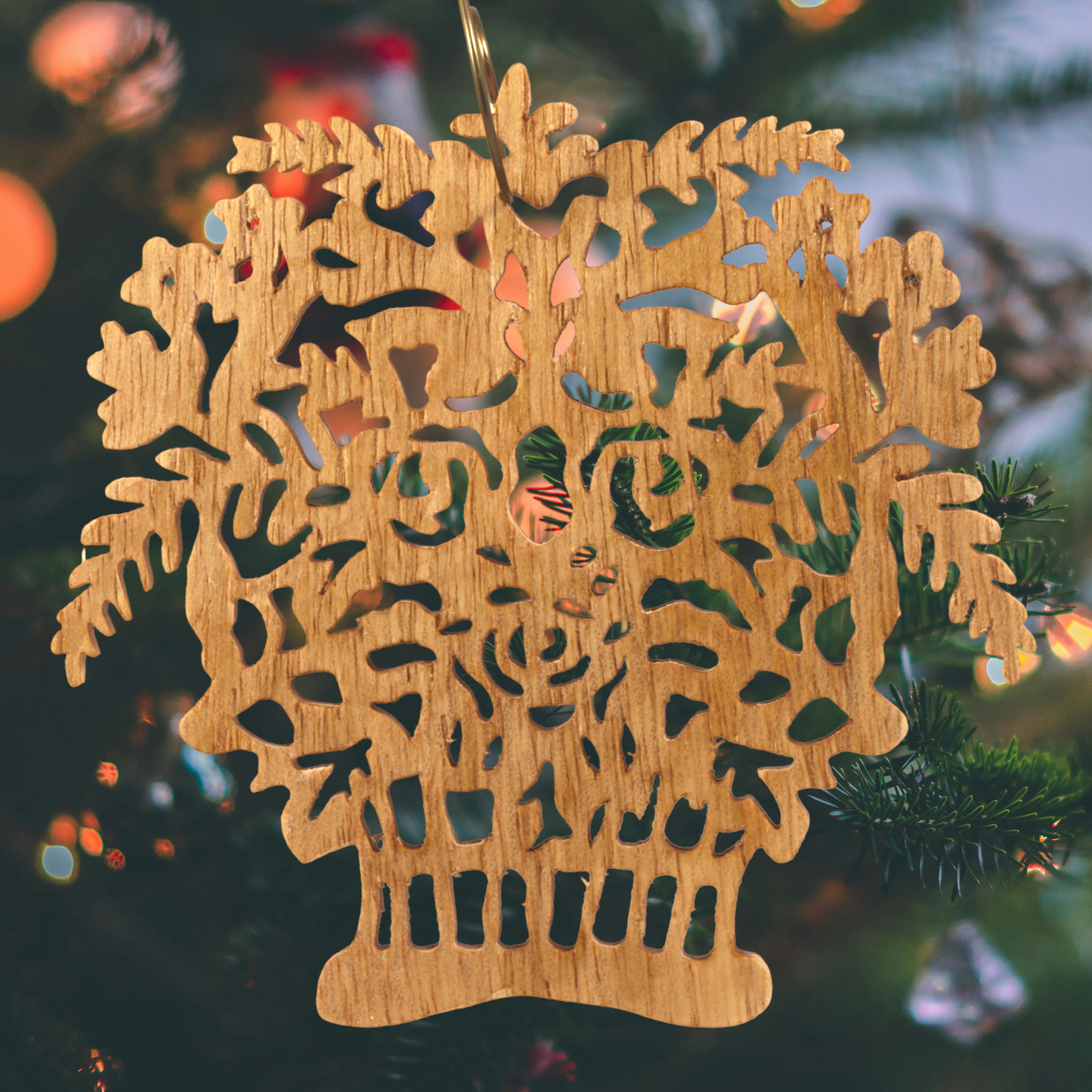 A handcrafted Victorian-style wooden Christmas tree ornament shaped like a basket filled with intricate floral designs, featuring detailed leaves and blossoms, with a small hook at the top for hanging.