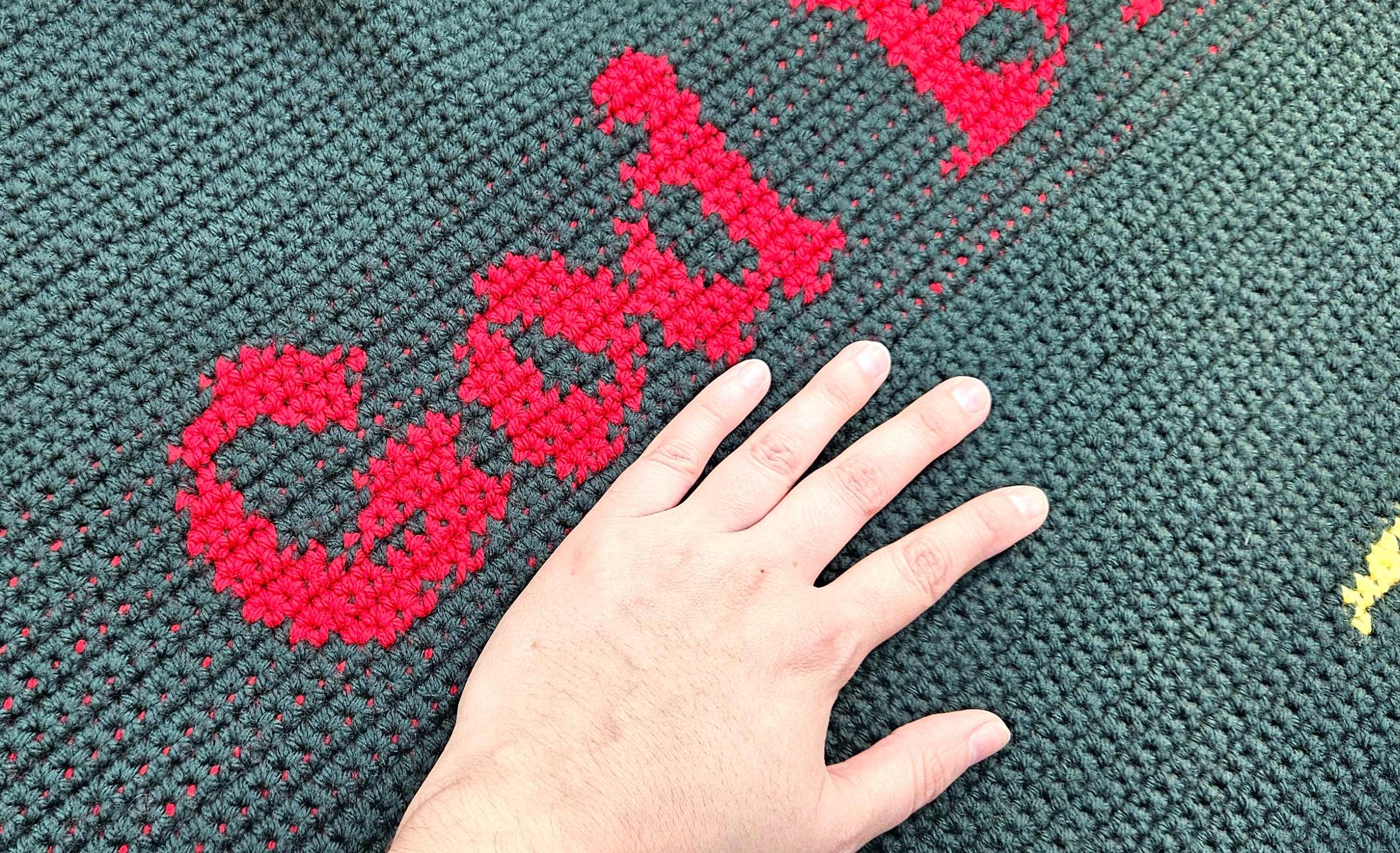 A close up of the word God in the God Bless Us Every One Tiny Tim quote. The maker's hand is in the photo for size context. A close up of the word God in the God Bless Us Every One Tiny Tim quote. The maker's hand is in the photo for size context.