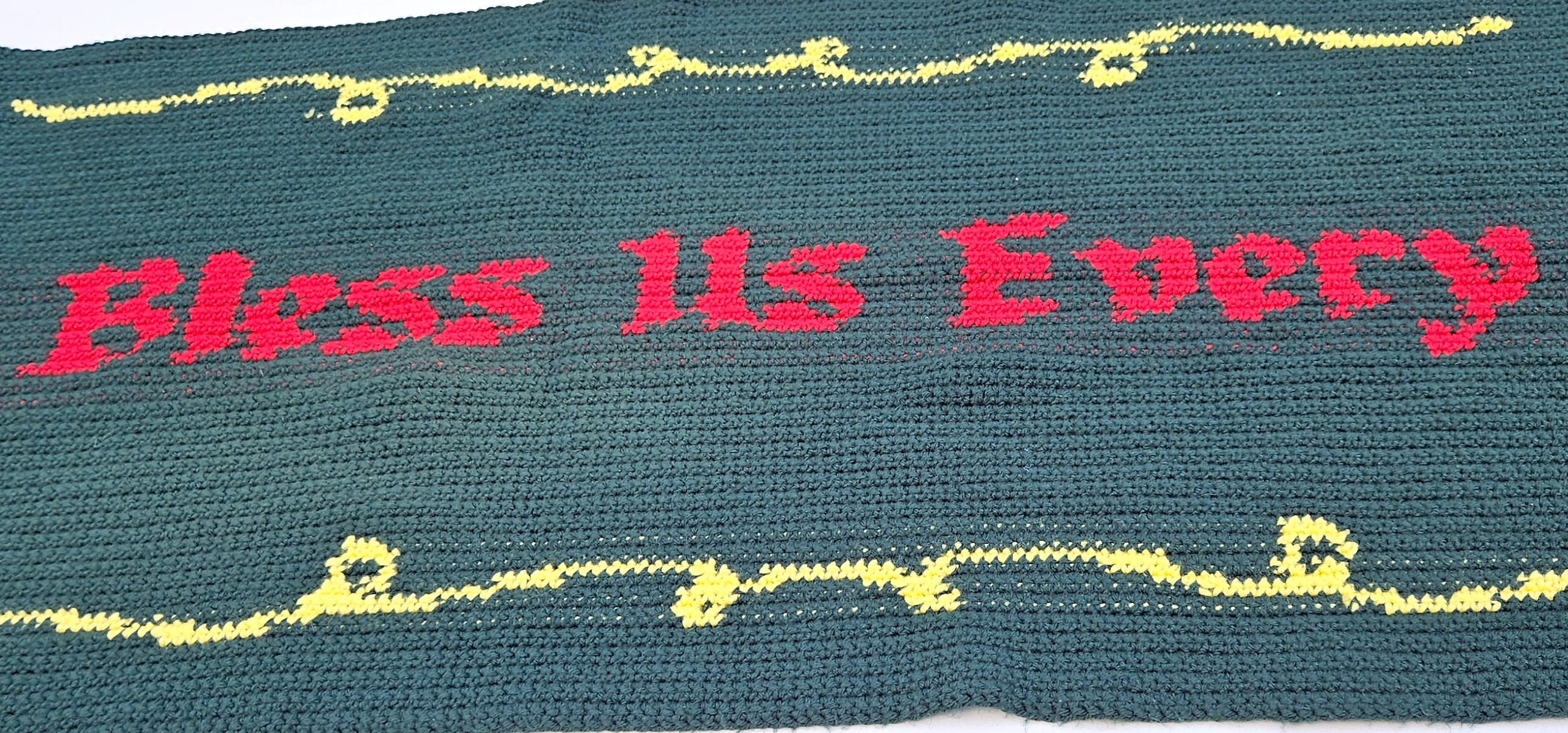 A close up of the words Bless Us Every in the center of the table runner. A close up of the words Bless Us Every in the center of the table runner.
