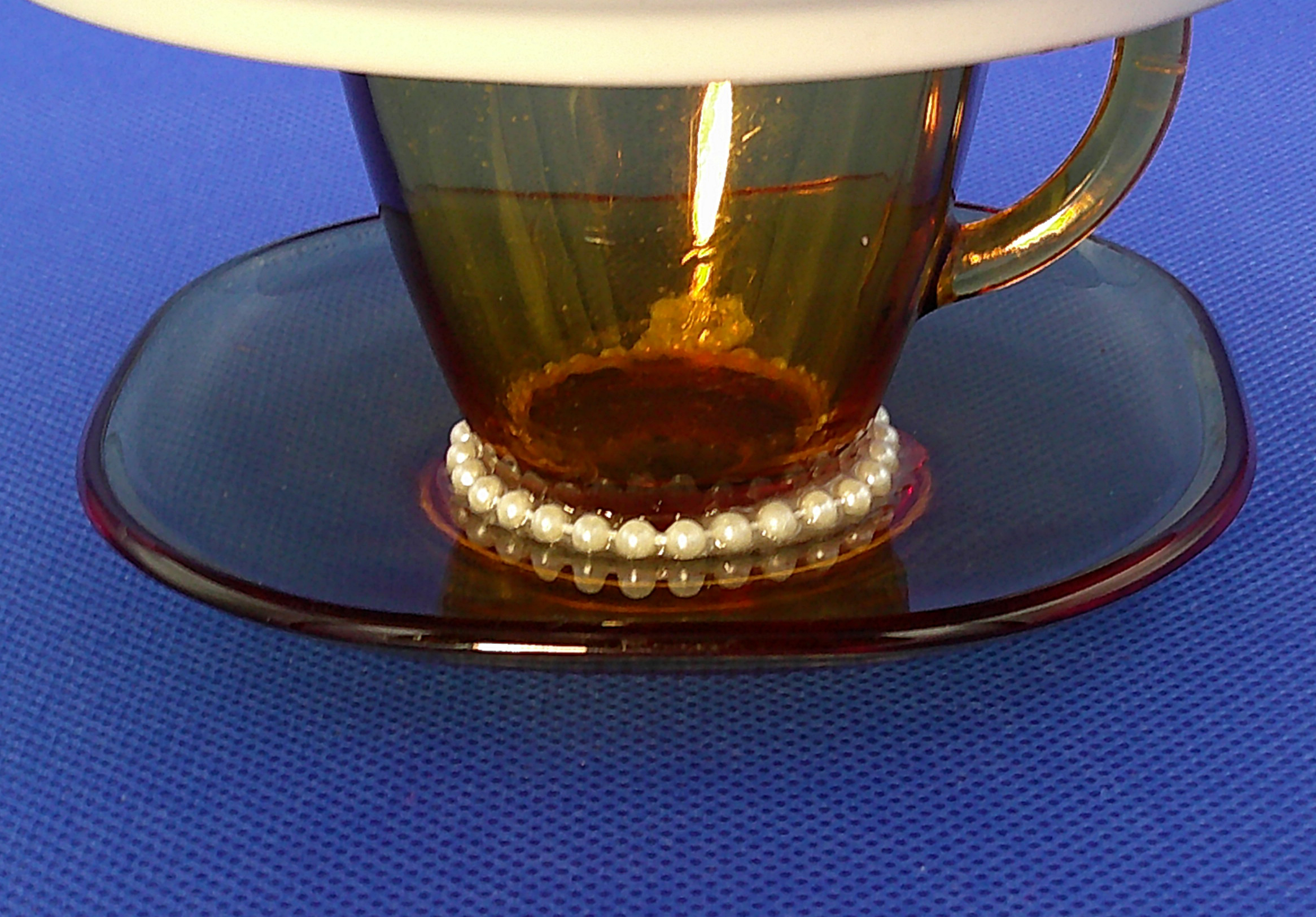The base of the demitasse cup and saucer with more pearls . The base of the demitasse cup and saucer with more pearls .