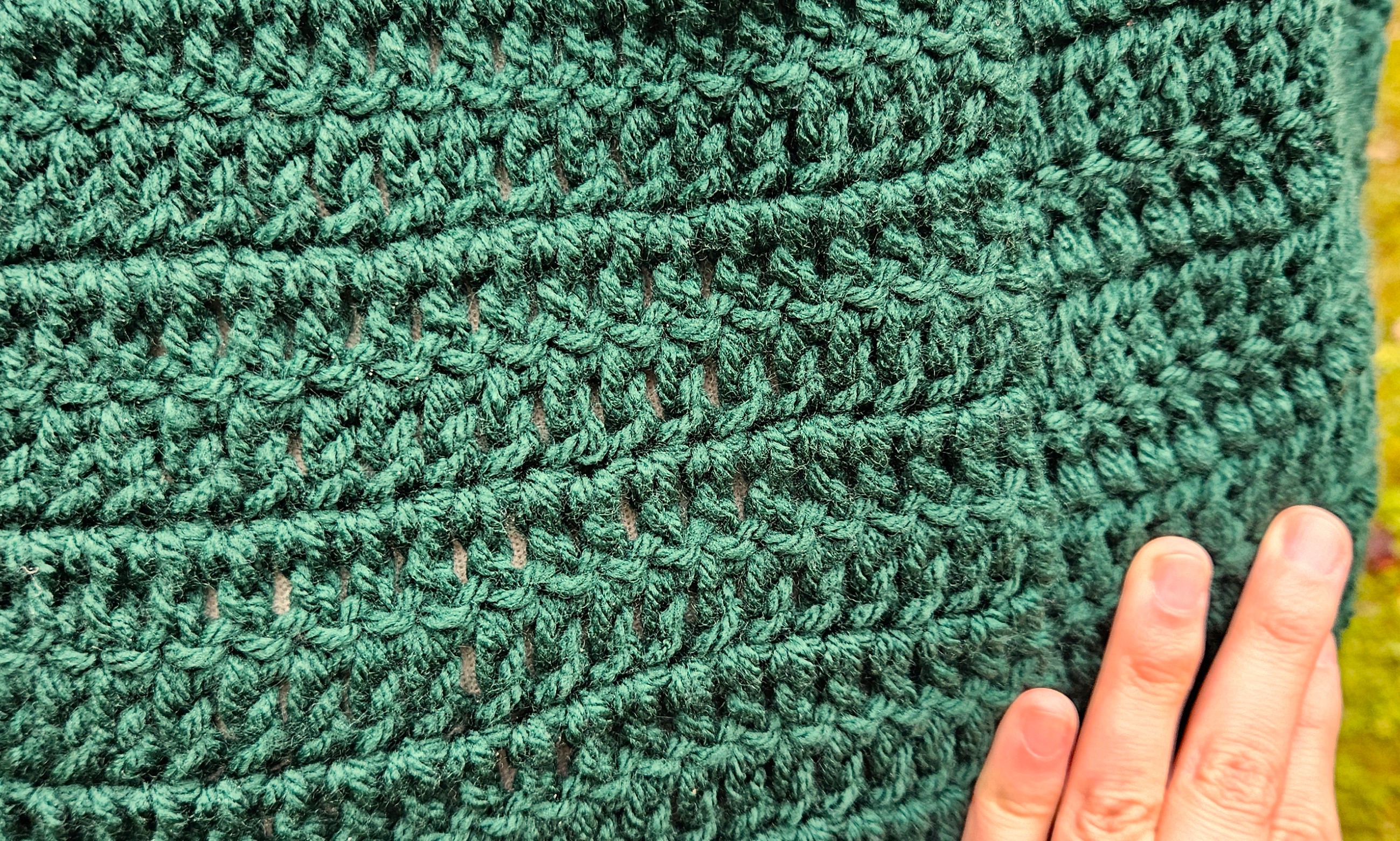 A close up of the green crochet stitches on the main scarf. The maker's fingers are in the photo for size context. A close up of the green crochet stitches on the main scarf. The maker's fingers are in the photo for size context.