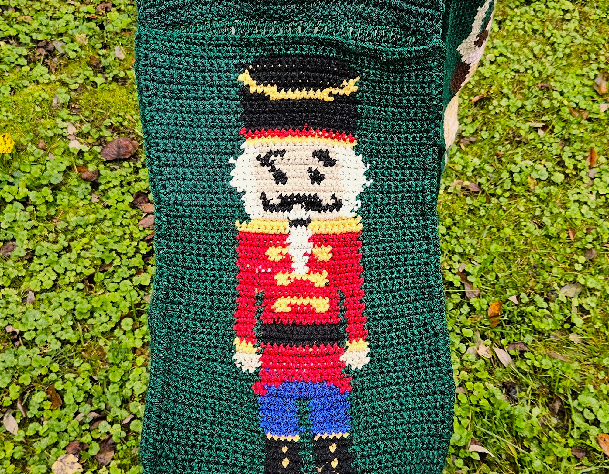 A close up of the Nutcracker pocket. He's wearing a red coat, blue pants, and black boots and hat, with yellow detailing. A close up of the Nutcracker pocket. He's wearing a red coat, blue pants, and black boots and hat, with yellow detailing.