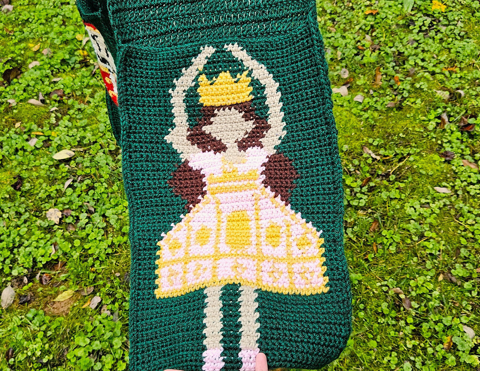 A close up of the ballerina pocket. She's wearing a pink dress with yellow details, and has brown hair, pale skin, and a yellow crown. A close up of the ballerina pocket. She's wearing a pink dress with yellow details, and has brown hair, pale skin, and a yellow crown.