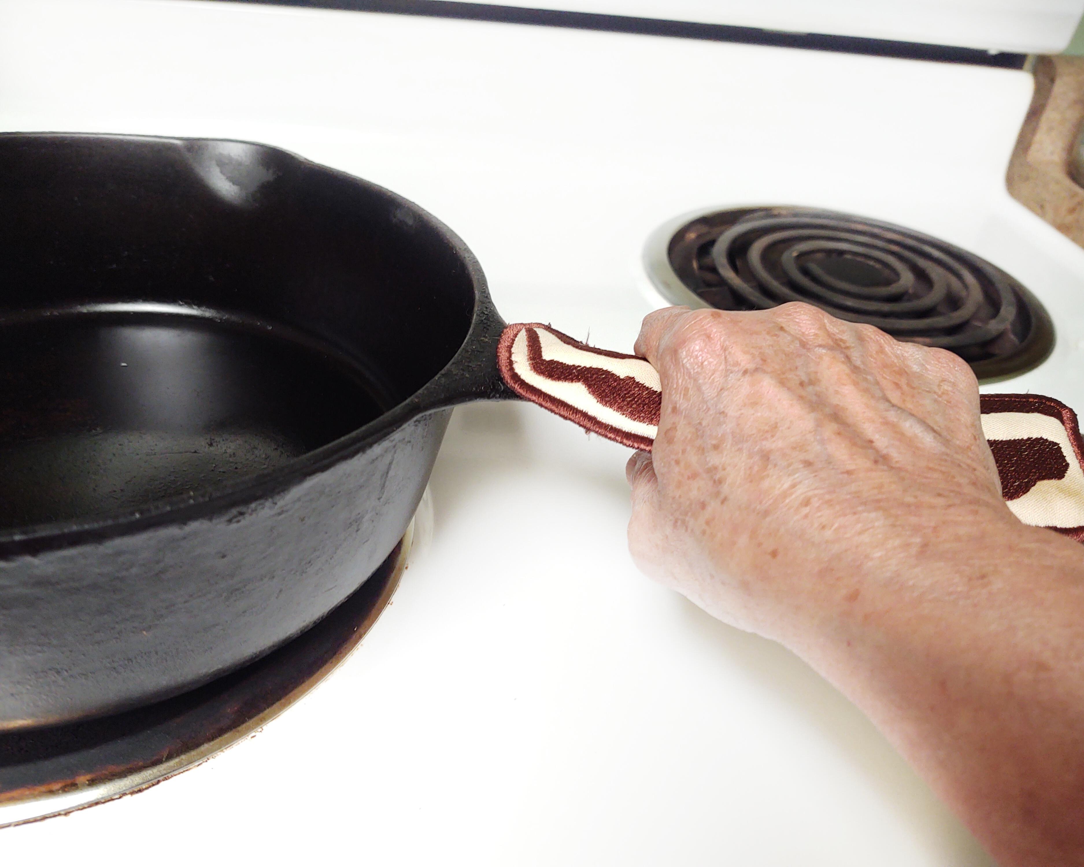 Pan handle sleeve shown in use on a cast iron skillet.