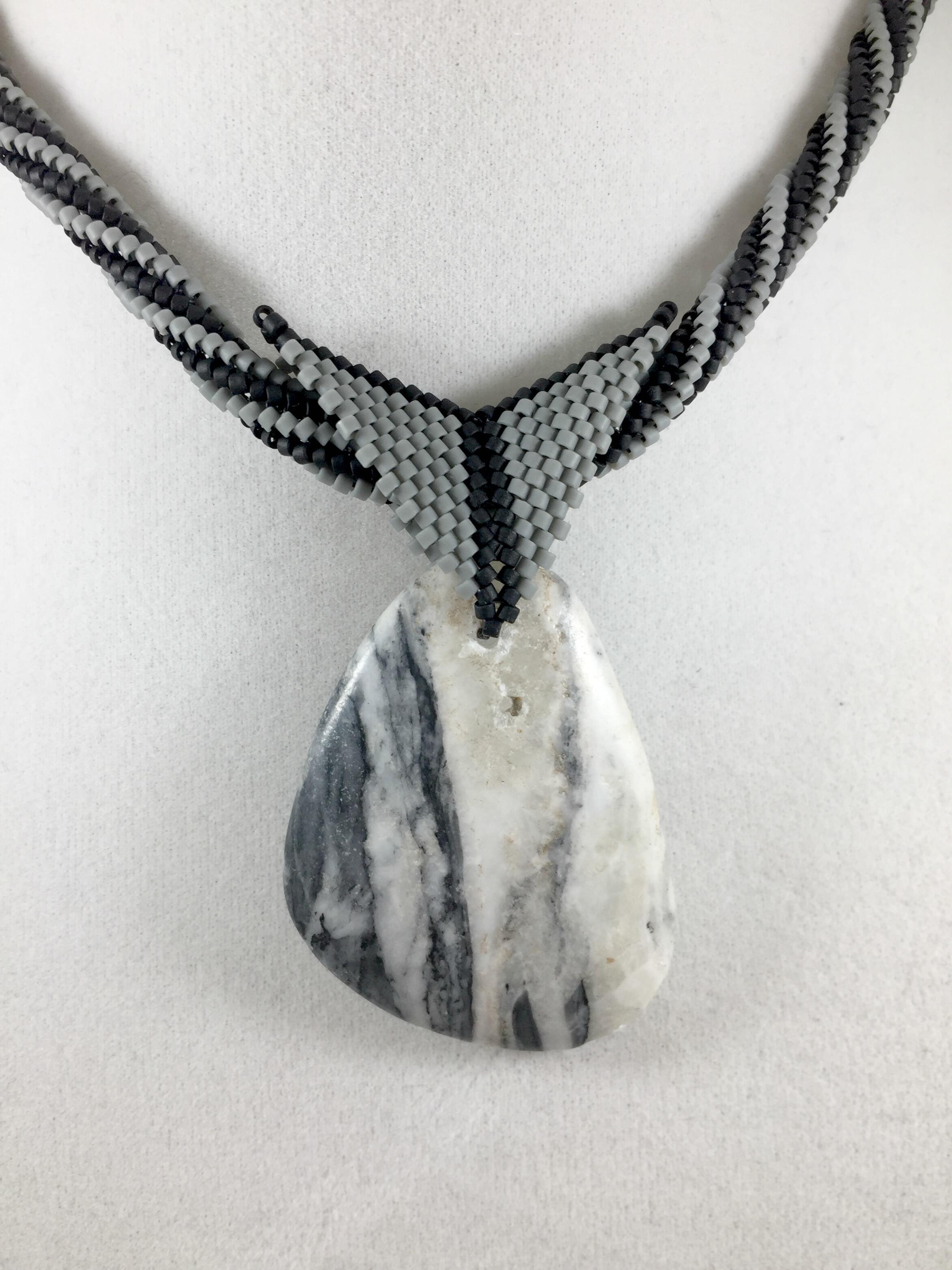 Close up image of grey and white marble pendant and beaded bail