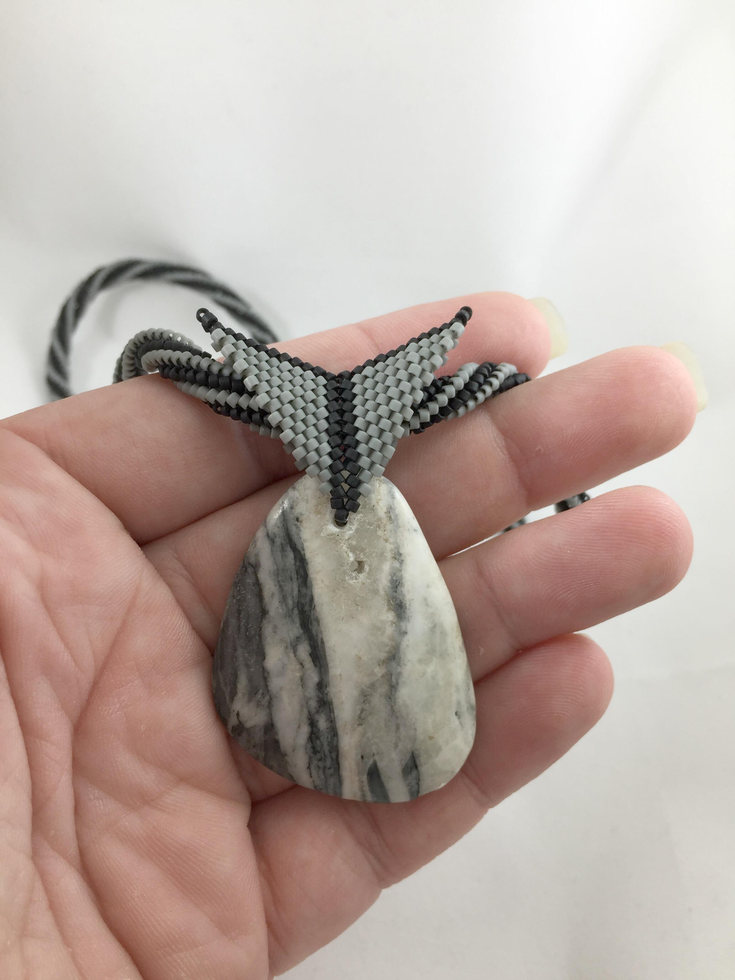 Grey and white marble pendant held in hand to show size