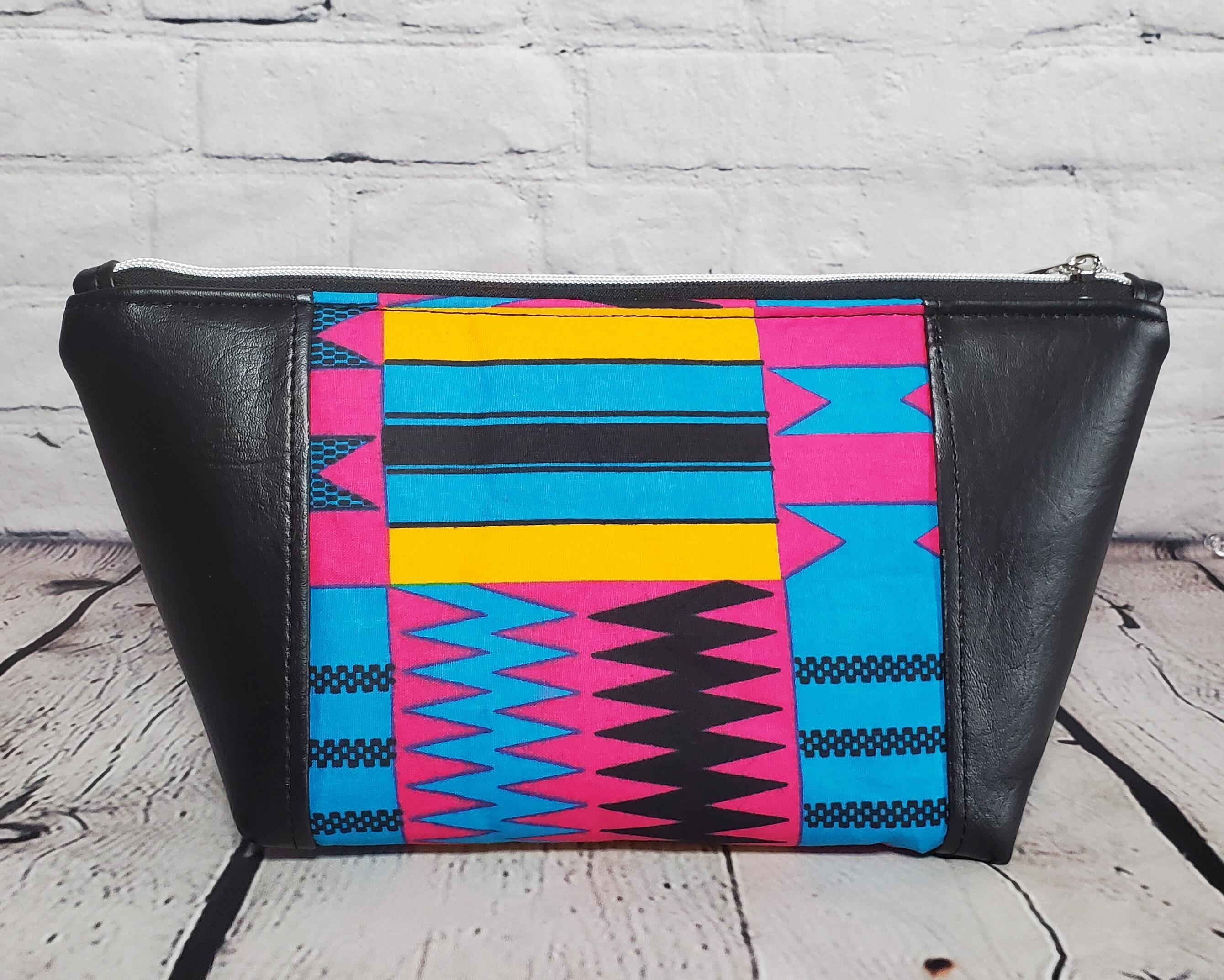 Pink blue and orange geometric print makeup bag with black faux leather accents, silver top zipper.