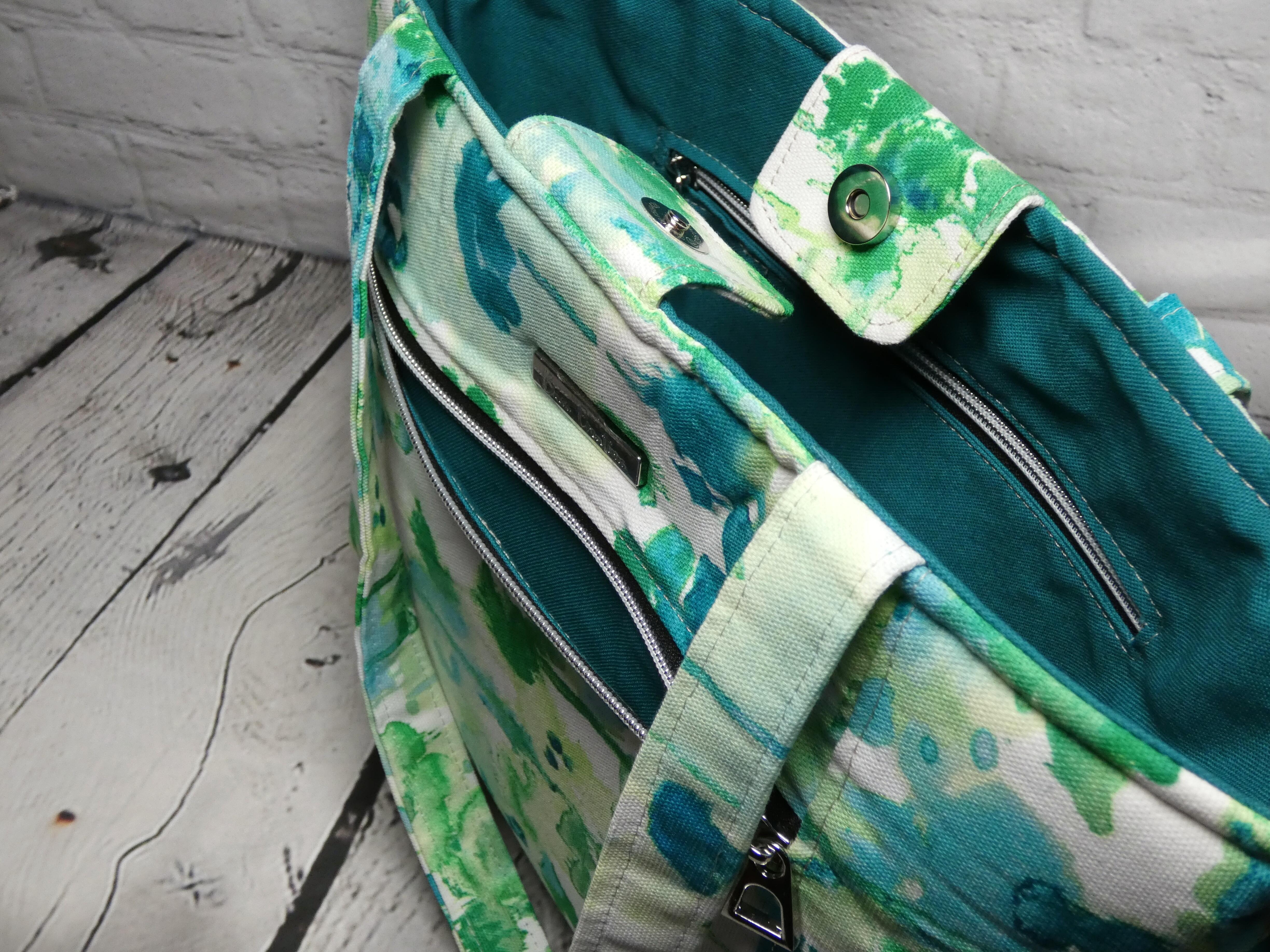 Top view of a market tote featuring the magnetic closure, green splotches outer fabric, and teal lining fabric.