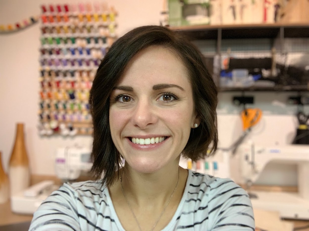 Kim smiling with colorful threads and sewing machines in background Kim smiling with colorful threads and sewing machines in background