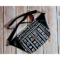 front view of a black and white tribal print waist bag with black faux leather accents, one zippered pocket, and silver hardware with a silver metal Bass Creations logo front view of a black and white tribal print waist bag with black faux leather accents, one zippered pocket, and silver hardware with a silver metal Bass Creations logo