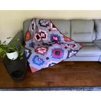 Handmade throw quilt, 54 X 63, in bold colors of bright pink, magenta, royal blue, burnt orange on a background of grayish orchid. Fabrics include striped cats and florals. Backing is a very bright pink with speckles of magenta and gold metallic.
