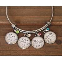 Silver wire bangle bracelet with 4 charms featuring names, birthdates, and birthstone charms. Silver wire bangle bracelet with 4 charms featuring names, birthdates, and birthstone charms.