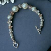 This is a beautiful handmade wedding bracelet. with white pearl beads and light pink faceted beads.  The clasp is a heart toggle.