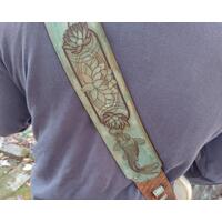 Japanese Koi and lotus flowers are featured on this intricately detailed handmade leather guitar strap with adjustable sizing for custom position height.

The base color of the main section of this strap is hand dyed in Moonlight Blue, which includes muted turquoise and tan tones.  The fish, water lillies, water and scale designs are permanently etched into the leather. The slot pieces are hand dyed in Antique Brown, with the adjustment pieces in Moonlight Blue