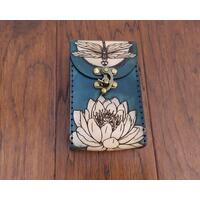 This Premium Handmade Leather Tarot Card Case features a dragonfly over moonlit water lilies. This is a unique 3 color premium leather tarot card box, hand dyed and hand sewn in our shop.

This special and unique find would make a beautiful gift for a tarot enthusiast in your life, or anybody looking to protect their tarot cards, oracle decks, or other small items. 

Featuring artwork permanently etched into the leather in black:

The front of this leather case displays a dragonfly over a full moon which is rising above a water lily.
The back of the case features a moonlit water garden, with water lilies glowing in the moonlight. 
Swirling shades of marbled blue are an interesting backdrop to the art. Our hand-dyed leather process produces an array of shades with incredible depth in the color. The natural character of the real full grain leather combined with the hand dying process makes each case unique.