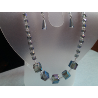 Denim glass jewelry set on a jewelry display. Statement necklace has focal point with larger square beads and tiny seed beads. Denim glass jewelry set on a jewelry display. Statement necklace has focal point with larger square beads and tiny seed beads.