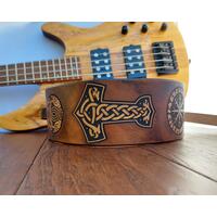 This is a Handmade Leather Guitar Strap Featuring a Viking or Norse motif. Crafted from ultra thick premium vegetable tanned leather, the instrument strap has been hand dyed and tooled, and the details are highlighted in natural tan for eye catching contrast.

Selected portions of the artwork are highlighted in natural tan, with the remainder of the strap hand dyed in a distressed Antique Dark Brown.