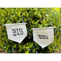 Two canvas pennant banners with different phrases that include Stay Wild and Wild & Brave.