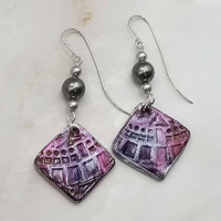 Purple and silver square dangles embossed with geometric shaped imprints hung with silver swarovski pearls. Handcrafted silver earring wires