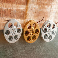 front view of a gold and silver miniature movie reel magnets hanging on fridge front view of a gold and silver miniature movie reel magnets hanging on fridge