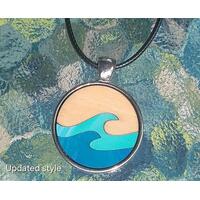 Round wooden necklace in stainless steel cabochon with black leather necklace. Birch wood has a natural on top with aqua and blue waves.