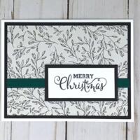 Merry Christmas card making kit with botanical scrapbook paper, black cardstock mat, stamped "Merry Christmas" sentiment and green ribbons.