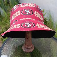Front view of bucket hat on stand. Fabric has red and gold SF 49ers logos on red background.