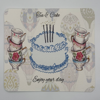 Watercolor design, hot air balloon background featuring cake with gold foil accented candles surrounded by teacups Watercolor design, hot air balloon background featuring cake with gold foil accented candles surrounded by teacups