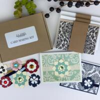 A handmade card making kit to make 6 cards with damask patterned paper, cardstock, die cut flowers, ribbons and cards and envelopes.