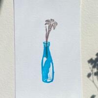 The front of this print features a lovely day lily sprouting out of a blue glass bottle.
