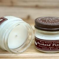 Apple cider scented soy candle in 4oz mason jar. One jar standing up with lid on and one jar on its side with lid off.