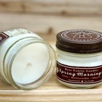 Lilac scented soy candle in 4oz mason jar. One jar standing up with lid on and one jar on its side with lid off.