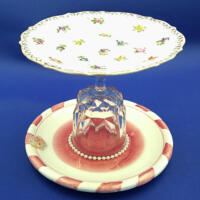 This lollypop jewelry dish has a dark pink and white dish on the bottom with pearls surrounding the crystal goblet. This lollypop jewelry dish has a dark pink and white dish on the bottom with pearls surrounding the crystal goblet.